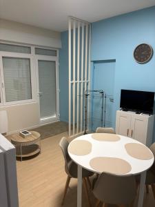 Una sala de estar con una mesa y sillas blancas. en Studio des dunes au clocher, en Berck-sur-Mer