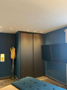ein Schlafzimmer mit einer blauen Wand, einem TV und einem Bett in der Unterkunft La parenthèse dorée in Les-Pennes-Mirabeau