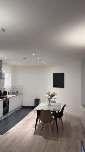una cocina blanca con una mesa con un jarrón de flores. en Spacious 4BR Apartment 7 Beds Near Station, en Newport 25 fotos más