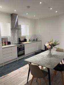 Una cocina con una mesa con un jarrón de flores encima. en Spacious 4BR Apartment 7 Beds Near Station, en Newport