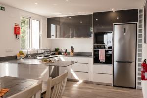 a kitchen with white cabinets and a stainless steel refrigerator at Casa Piquita in Estreito da Calheta