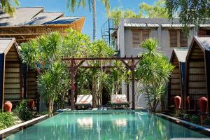 a swimming pool in front of a house with palm trees at Waras Villa in Gili Trawangan