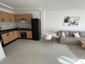 a kitchen and a living room with a couch and a table at Modern Coastal Apartment in Kenitra