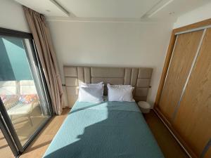 a small bedroom with a bed with a window at Modern Coastal Apartment in Kenitra