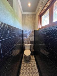 a bathroom with a toilet and blue tiled walls at Waras Villa in Gili Trawangan +33 photos