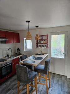 una cucina con mobili rossi, tavolo e sedie di Casă mică și șarmantă la țară a Plonévez-du-Faou