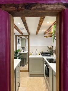 eine Küche mit weißen Arbeitsflächen und einer lila Decke in der Unterkunft Curiosity Cottage in Wendover