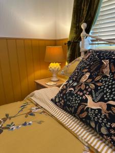 ein Schlafzimmer mit einem Bett und einer Lampe auf einem Tisch in der Unterkunft Curiosity Cottage in Wendover