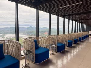 une rangée de chaises avec des tables bleues et des fenêtres dans l'établissement Wyndham Lynn Times Thanh Thuỷ - Căn hộ khách sạn Onsen 5 sao, à La Phu