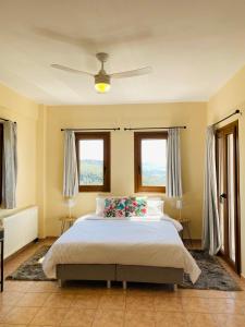 a bedroom with a large bed and two windows at Sun Touch Pelion Rooms in Kala Nera