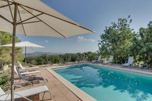 a swimming pool with chairs and an umbrella at Finca Moscari in Madrid
