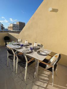 een tafel met stoelen en borden erop op een terras bij Mahogany - Rooftop Views - Close to Valletta Ferry in Senglea