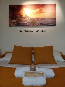 a bed with towels on it with a picture on the wall at La Palazzina dei Fiori in Bari