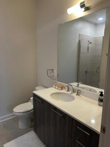 Un baño con lavabo, inodoro y espejo. en Altura Apartment Arlington, en Arlington