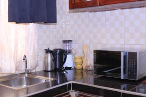 a kitchen counter with a sink and a microwave at Tasha's suites in Entebbe +1 photo