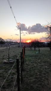 une clôture dans un champ avec le coucher de soleil en arrière-plan dans l'établissement Pura Vida, à Cortaderas