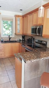 a kitchen with wooden cabinets and a granite counter top at Sooke Harbour Hideaway - Luxurious Vacation Rental in Sooke