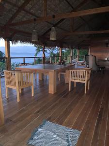 a table and benches on a deck with the ocean at Scavana lodge in Nosy Be