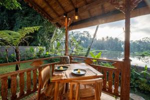 a wooden table and chairs on a balcony with a view at Umah Merta Kayu in Ubud