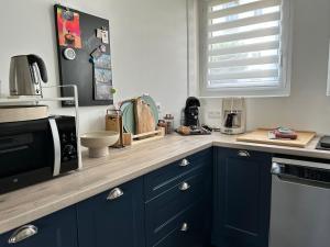 une cuisine avec des armoires bleu marine et un four micro-ondes dans l'établissement Bel Appartement , proche tram place de Strasbourg accès centre ville, plages, à Brest
