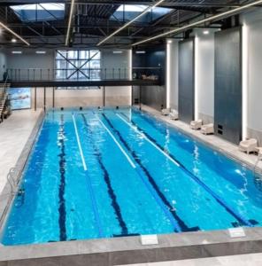 a large indoor swimming pool with blue water at Cozy 2-Bedroom flat with Terrace & Parking by Alfa in Rīga