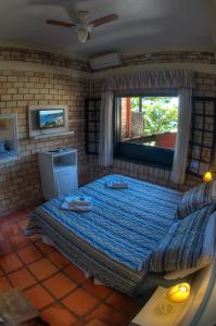 a bedroom with a large bed with a window at Pousada da Encosta in Garopaba
