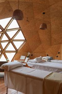 two beds in a room with a large window at Domos Mare - Glamping frente al Mar in Quequén
