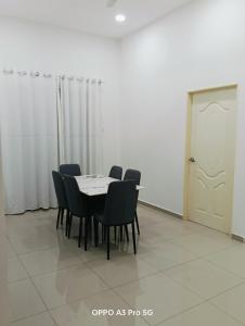 a dining room with a table and chairs and a door at Homestay Garden view in Kuantan