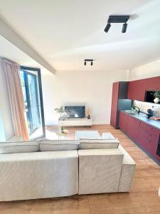 a living room with two white couches and a kitchen at Moderný apartmán so súkromnou terasou v centre mesta in Banská Bystrica