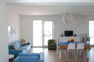 ein Wohnzimmer mit einem blauen Sofa und einem Tisch und Stühlen in der Unterkunft Villa Chiara in Pozzallo