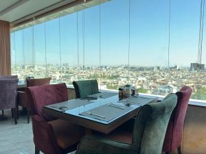 una sala da pranzo con tavolo e sedie e una grande finestra di Al Jawahiri Hotel a Erbil