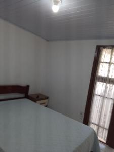 a bedroom with a white bed and a window at Casario in Florianópolis