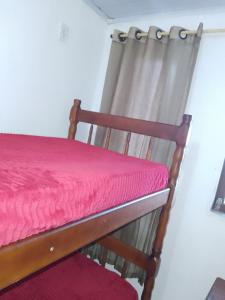 a wooden chair with a pink mattress and a curtain at Casario in Florianópolis