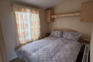 a small bedroom with a bed and a window at Sand Le Mere Caravan in Tunstall +10 photos