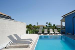 ein Swimmingpool mit Liegestühlen neben einem Gebäude in der Unterkunft Villa Chiara in Pozzallo