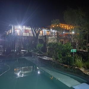 a swimming pool at night with a building in the background at Nkisi Guesthouse in Kang