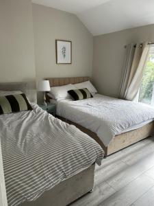 two beds in a white bedroom with a window at Luxury 3 Bed House - 10 min walk from Dartford Town Centre - Fully Refurbished in Dartford