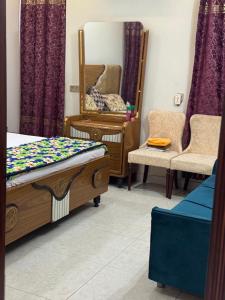 ein Schlafzimmer mit einem Bett, einem Spiegel und einem Stuhl in der Unterkunft Multan house in Multan