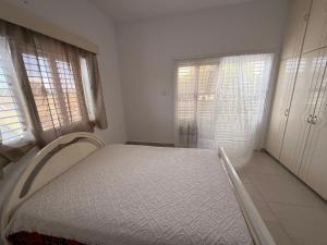 ペリヴォリアにあるCozy 2BR in Pervolia Near Beach Free Parking and many moreの白いベッドルーム(ベッド1台、窓2つ付)