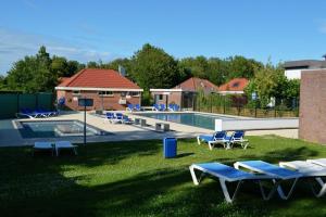 a swimming pool with lounge chairs in the grass at Lavendel Huisje in Herkingen