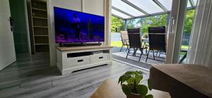a living room with a flat screen tv on a stand at Lavendel Huisje in Herkingen