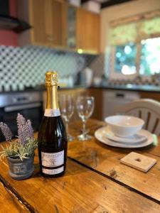 a bottle of wine sitting on a wooden table with glasses at Traditional Country Cottage in Chew Magna