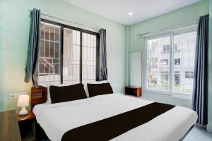 KhānāpāraにあるHotel O The Pride Inn Basistha Roadの大きなベッドと2つの窓がある寝室