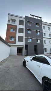 MawāliḩにあるNear Airport Roomsの建物の前に駐車された白い車