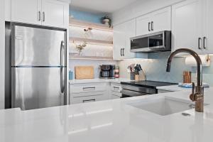 a kitchen with white cabinets and a stainless steel refrigerator at Sea La Vie - Pelican Beach Resort in Destin