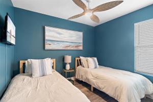 two beds in a blue room with a ceiling fan at Sea La Vie - Pelican Beach Resort in Destin +51 photos
