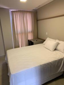 a bedroom with a large white bed with a window at UNO Flats 104 - 50m from the beach in João Pessoa