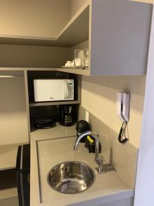a kitchen counter with a sink and a microwave at UNO Flats 104 - 50m from the beach in João Pessoa