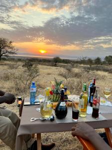 a picnic table with bottles and glasses of wine at Furaha Luxury Lodge in Mto wa Mbu