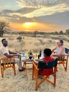 a group of people sitting around a table in the desert at Furaha Luxury Lodge in Mto wa Mbu